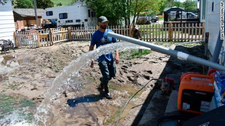 Micah Hoffman uses a pump to remove water from the basement of his Road Lodge, Montana, home.