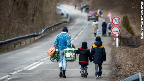 A woman with two children and carrying bags walk on a street to leave Ukraine after crossing the Slovak-Ukrainian border in Ubla, eastern Slovakia, close to the Ukrainian city of Welykyj Beresnyj, on February 25, 2022, following Russia&#39;s invasion of the Ukraine. - Ukrainian citizens have started to flee the conflict in their country one day after Russia launched a military attack on neighbouring Ukraine. (Photo by PETER LAZAR / AFP) (Photo by PETER LAZAR/AFP via Getty Images)