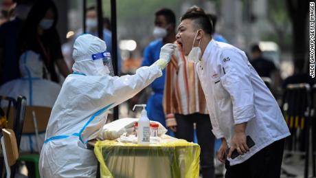 Een gezondheidswerker neemt een uitstrijkje van een man op een geïmproviseerde testlocatie buiten een winkelcentrum in Peking, 15 juni 2022.