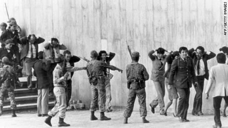 Militares colombianos protegen a un grupo de magistrados saliendo del Palacio de Justicia de Bogotá el 6 de noviembre de 1985. 