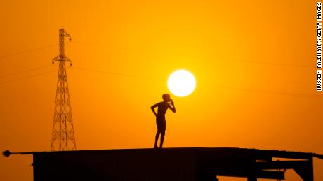A boy prepares to jump off the roof of a structure to cool off in the waters of the Shatt al-Arab waterway, formed at the confluence of the Euphrates and Tigris rivers, in Iraq&#39;s southern city of Basra near sunset on June 18.