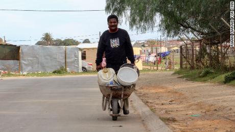 Morris Malambile says pushing a wheelbarrow full of water containers every day is 
