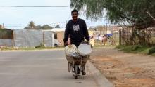 Morris Malambile says pushing a wheelbarrow filled with water containers every day is &quot;tiring.&quot;