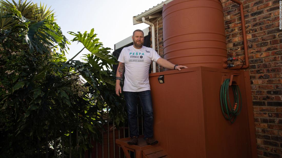 Rhett Saayman standing next to one of his several water tanks at his home in Kamma Heights.