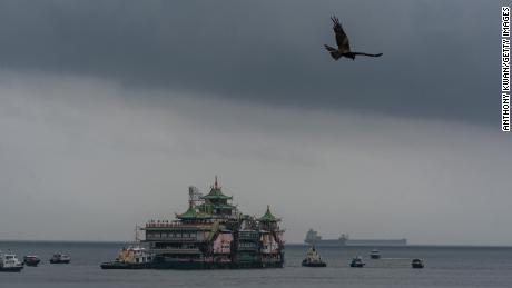 A bird flies over the floating Chinese imperial style jumbo restaurant as it is pulled from typhoon shelter in Hong Kong on June 14, 2022.