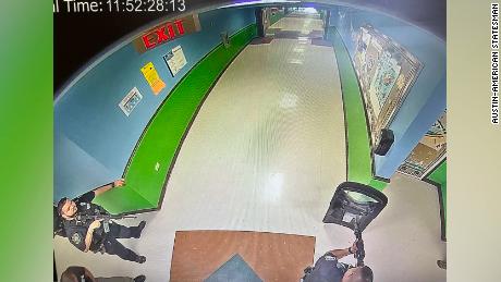 Une photo obtenue par l'Austin-American-Statesman montre au moins trois officiers dans le couloir de Rapp Elementary à 11 h 52, 19 minutes après l'entrée du tireur dans l'école.  Un officier tient ce qui semble être un bouclier tactique, tandis que deux officiers tiennent des armes à feu.
