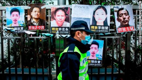 A police officer walks past placards calling for the release of detained Chinese rights activists taped on the fence of the Chinese liaison office in Hong Kong on February 19, 2020.