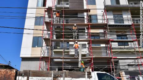 Des ouvriers du bâtiment passent des planches de bois lors de la construction de nouveaux appartements à Monterey Park, en Californie.