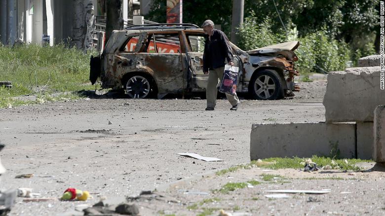 ชายคนหนึ่งเดินผ่านซากปรักหักพังของรถยนต์ใน Lysychansk เมื่อวันที่ 21 มิถุนายน 2022 ขณะที่ยูเครนกล่าวว่าการใช้กระสุนปืนของรัสเซียทำให้เกิด "การทำลายล้างอย่างร้ายแรง"  ในเมืองอุตสาหกรรมตะวันออก