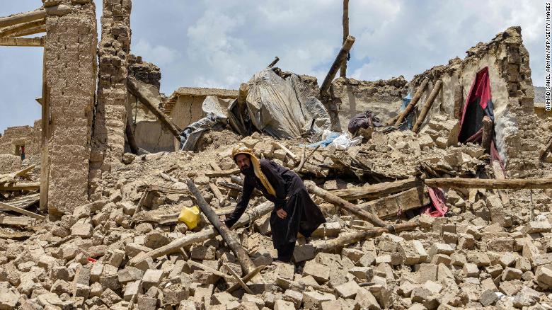 An Afghan man looks for his belongings amid the ruins of a house damaged by an earthquake.