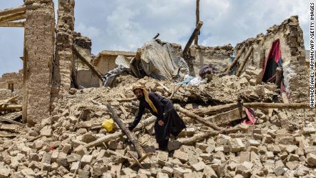 Afgan bir adam, depremde hasar gören bir evin yıkıntıları arasında eşyalarını arıyor. 