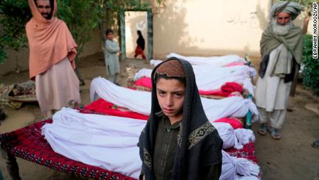Homens ficam ao redor dos corpos das pessoas mortas em um terremoto em 23 de junho na vila de Gayan, na província de Paktika, no Afeganistão.