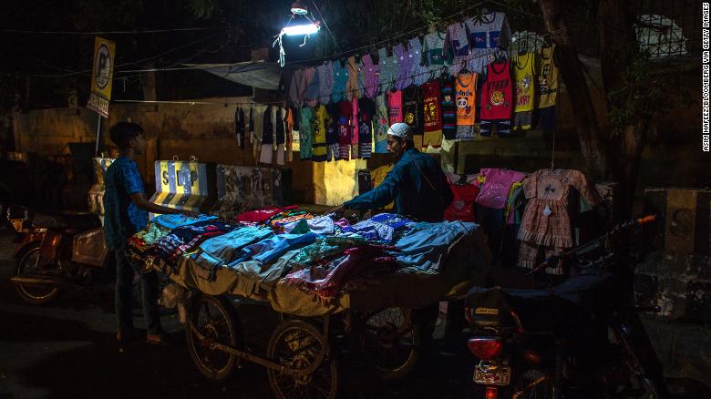 A vendor sells fabrics under an emergency light connected to a motorcycle during a load-shedding power outage in Karachi, Pakistan on June 8.