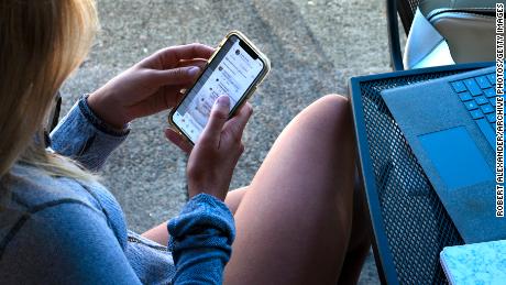A young woman uses her smartphone as she sits outside a coffee shop in Jacksonville, Oregon. 