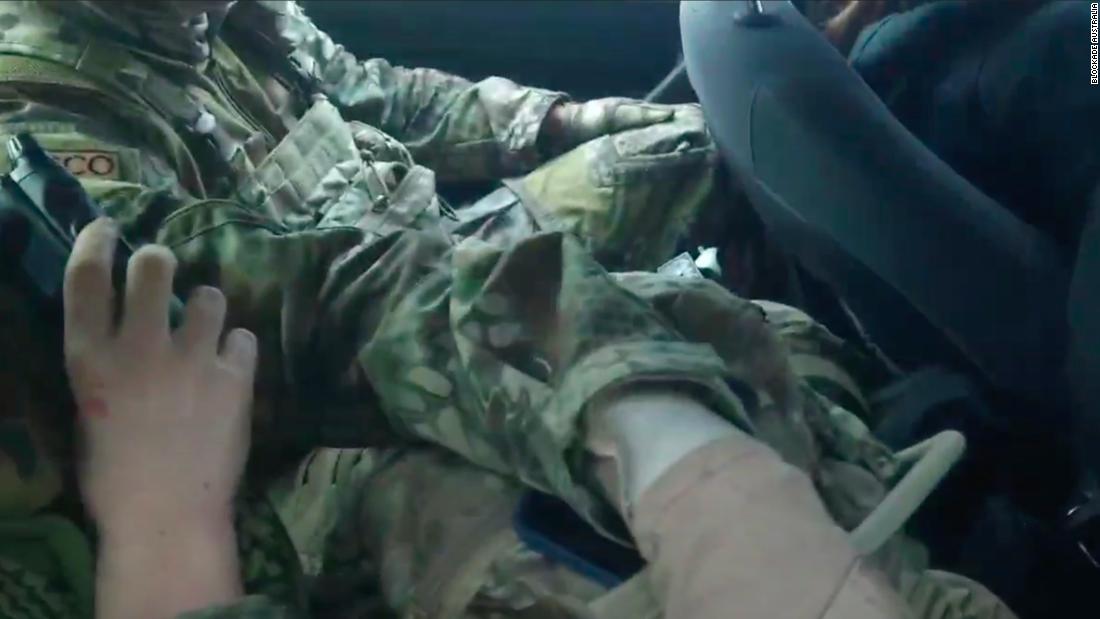 People in camouflage sitting in a car surrounded by activists after being discovered on a private property near Sydney. 