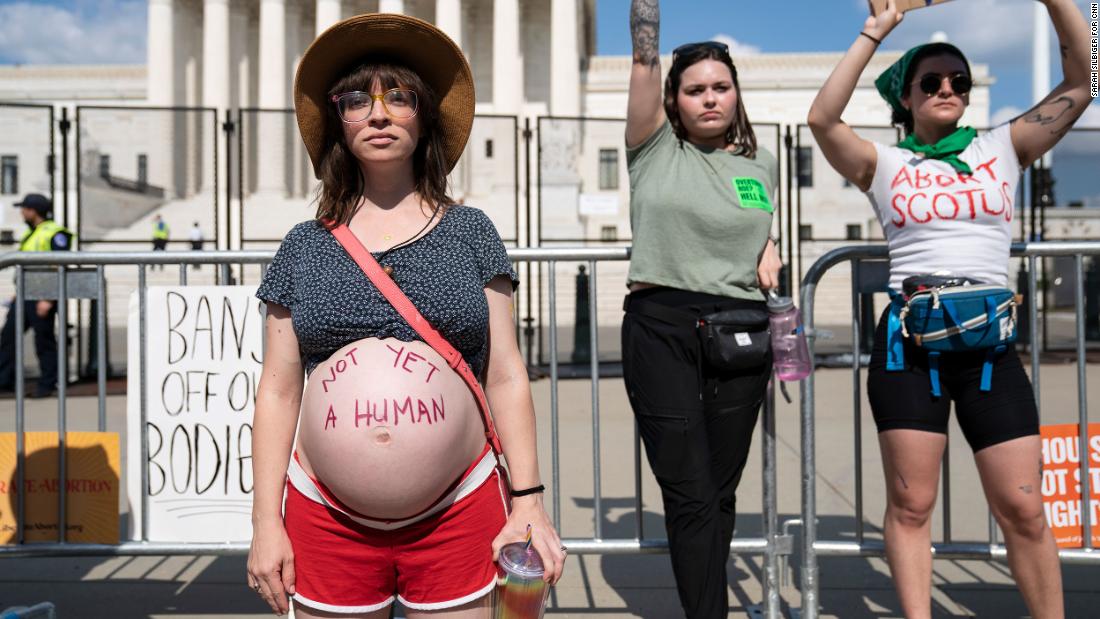 Amanda Herring, left, poses for a portrait with the words &quot;not yet a human&quot; written on her pregnant belly during an abortion rights demonstration in front of the Supreme Court on Friday. Herring, who is Jewish, told CNN that her religion has helped shape her views on abortion. &quot;Judaism says that life begins with the first breath, that is when the soul enters the body,&quot; she said.