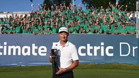 Li poses with the winner&#39;s trophy on the 18th green alongside event volunteers.