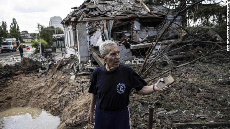 A man inspects a bomb crater after Russian artillery shells hit a district of Kharkiv on June 26, 2022.