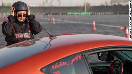 Afnan Almarglani, la première femme saoudienne à être certifiée comme monitrice d'autocross, ajuste son casque devant sa voiture sur le circuit de Derab à Riyad, la capitale saoudienne, le 26 juin. 