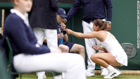 İngiltere'nin Jodie Burrage ilk tur Wimbledon maçında elinde şekerlemelerle hasta olan top çocuğunun yardımına koşuyor.