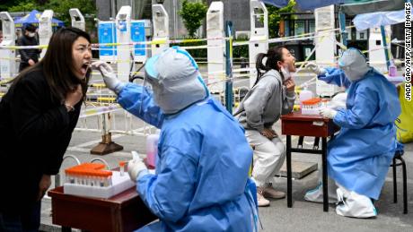 Op 11 mei 2022 nemen gezondheidswerkers ruilmonsters voor een Govt-19-test op een geïmproviseerde testlocatie in een straat in Peking.