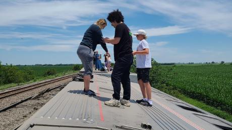 People stand on the side of an overturned Amtrak train in Montenegro, Missouri.