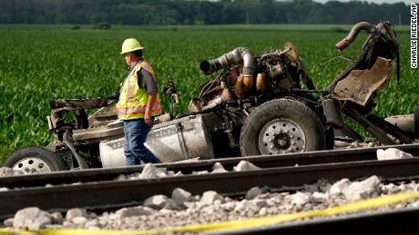 A worker looks over a dump truck that collided with an Amtrak train, causing it to derail.