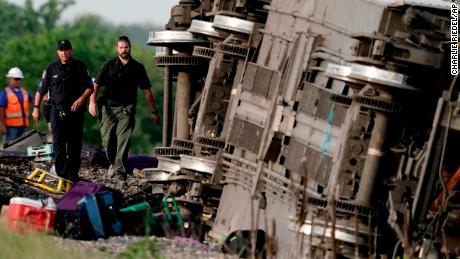 Law enforcement officers inspect the footage of an Amtrak train that derailed after hitting a dump truck Monday near Mendon, Missouri.