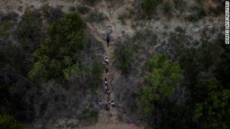 Migrant families climb a steep bank after crossing the Rio Grande into the US on June 16.