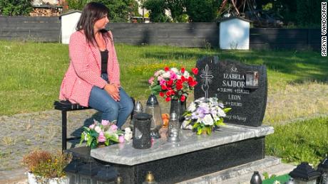 Barbara Skrobol, la belle-sœur d'Izabela, est assise à côté de sa tombe dans le sud de la Pologne.