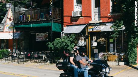 Riders on a motorcycle drive by a restaurant in downtown Eureka Springs on June 21.