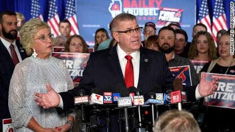 Republican gubernatorial primary candidate Darren Bailey, center, stands with his wife, Cindy Stortzum, and responds to reporters&#39; questions after winning the Republican gubernatorial primary, Tuesday, June 28, 2022, in Effingham, Ill. Bailey will now face Democratic Gov. J.B. Pritzker in the fall. 