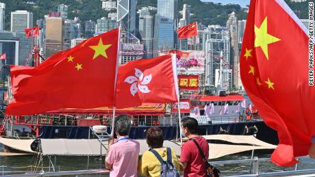 People wave Chinese and Hong Kong flags as fishing boats carrying banners celebrating the 25th anniversary of Hong Kong&#39;s handover to China sail through the Victoria Harbour.