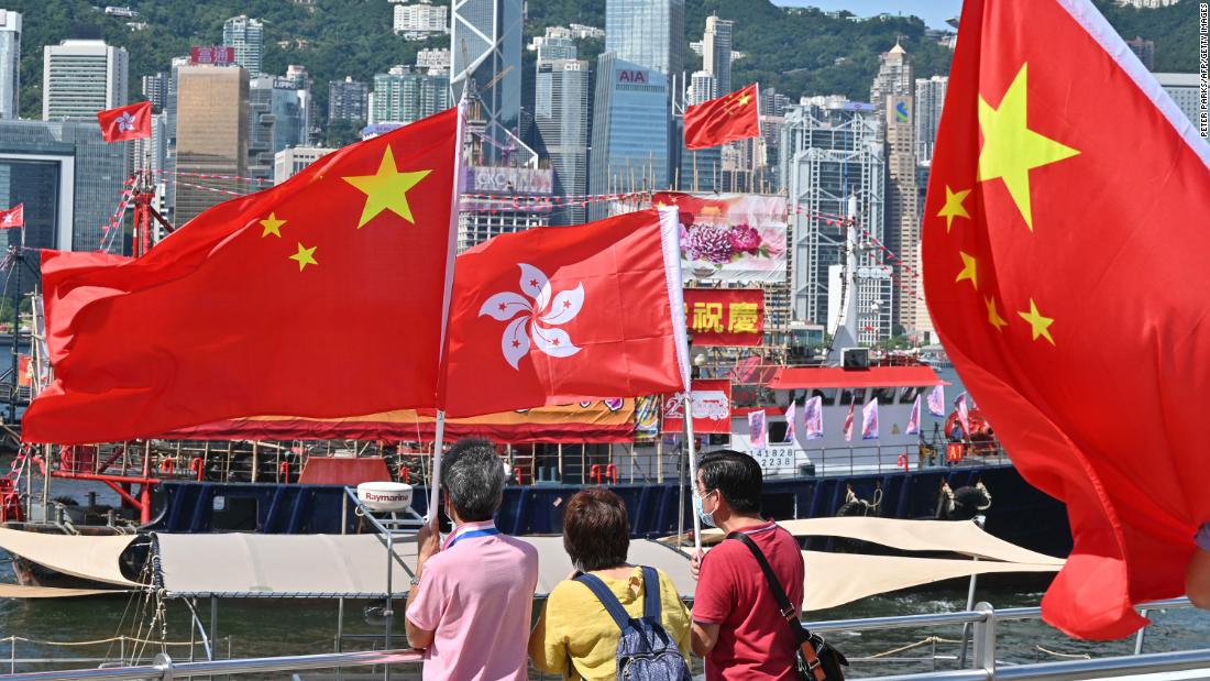 People wave Chinese and Hong Kong flags as fishing boats carrying banners celebrating the 25th anniversary of Hong Kong's handover to China sail through the Victoria Harbour.