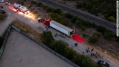 In this aerial view, law enforcement officers investigate a tractor-trailer on June 27, 2022 in San Antonio, Texas.  More than 50 people were found dead in an abandoned tractor-trailer. 