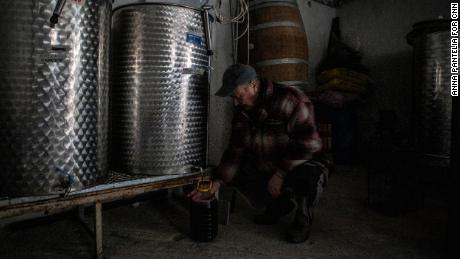 Dimitris Matisaris' father, a former checkpoint worker, fills a bottle of wine at his son's winery.