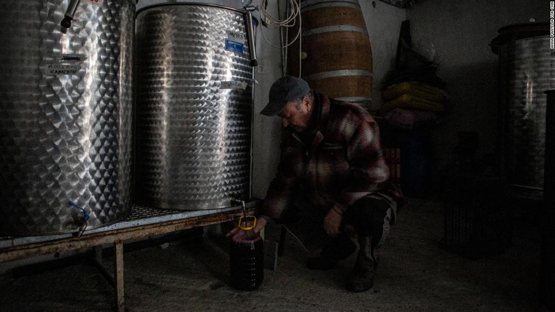 Dimitris Matisaris&#39; father, a retired PPC worker, fills a bottle of wine at his son&#39;s winery.