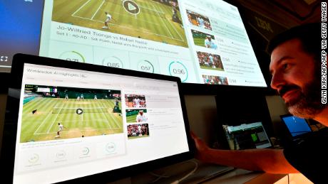 An IBM technician poses with screens showing AI-generated highlights during Wimbledon 2019. The tournament has partnered with IBM to educate fans at the 2022 tournament.