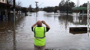 A local takes a photo of a road inundated by floodwaters in Camden in South Western Sydney, Sunday, July 3, 2022.