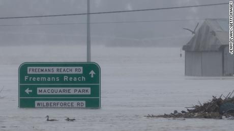 Street signs are seen submerged under flood water along the Hawkesbury River in the suburb of Windsor on July 4, 2022.