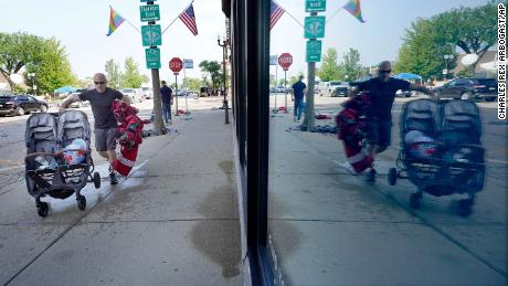 Highland Park resident Murry Rosenbush is reflected in a store window Tuesday as he removes items left behind by attendees to the town&#39;s Fourth of July parade.