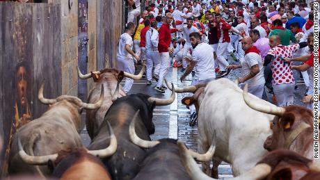 Revelers run alongside the fighting bulls of the Nunez del Cuvillo ranch during the first day of running of the bulls at the San Fermin Festival in Pamplona, northern Spain, on July 7, 2022. Revelers from all over the world flock to Pamplona every year to participate in the eight days of bullfighting. Made famous by American writer Ernest Hemmingway&#39;s 1926 novel &#39;The Sun Also Rises&#39;, the annual San Fermin Festival involves the daily running of the bulls through the historic heart of Pamplona to the bullring  