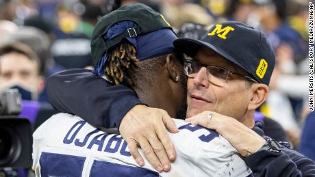 Ojabo y el entrenador en jefe de Michigan, Jim Harbaugh, se abrazan después de un partido contra los Iowa Hawkeyes.