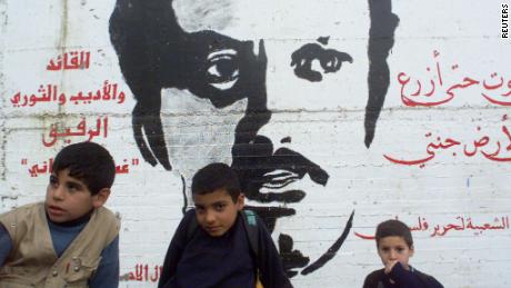 Palestinian refugee school children sit by a wall painting featuring Palestinian writer Ghassan Kanafani in the Dheisheh refugee camp in the outskirts of Bethlehem January 4, 2001. 