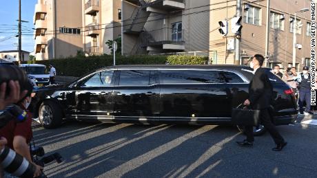 A car believed to be carrying Shinzo Abe&#39;s body passes by police officers and media outside the Nara Medical University Hospital in Kashihara, Nara prefecture on July 9.