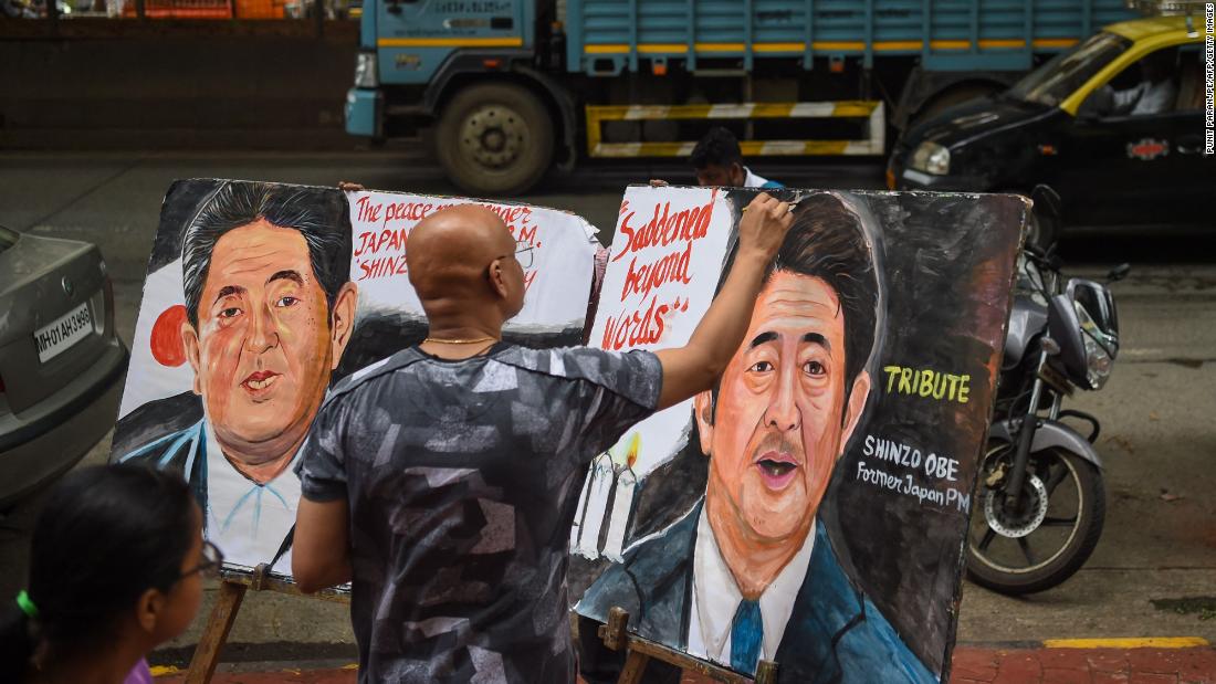 An artist in Mumbai, India, puts the final touches on a couple of Abe tribute paintings.