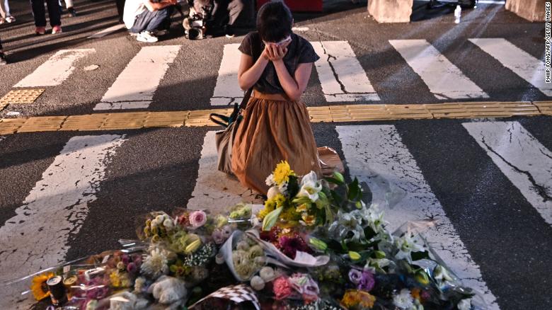A woman prays in front of a makeshift memorial at the scene outside Yamato-Saidaiji Station in Nara where former Japanese prime minister Shinzo Abe was shot.