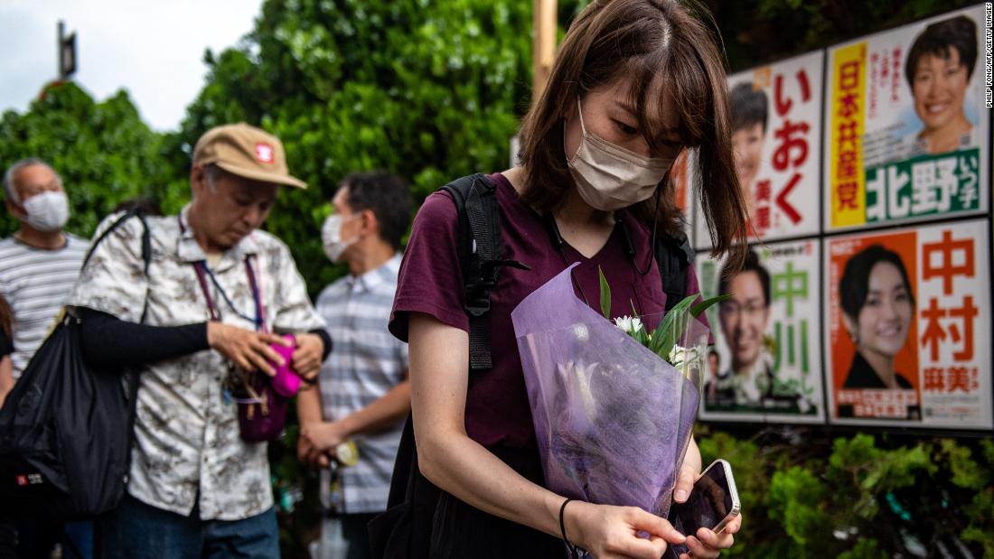 People line up to place flowers at a makeshift memorial where Abe was shot on Friday.