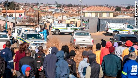 Orang-orang berkumpul di lokasi penembakan bar semalam di Soweto, Afrika Selatan, Minggu 10 Juli 2022. 