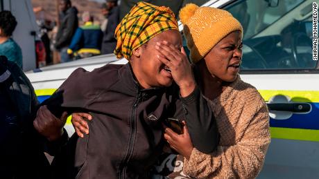 A woman weeps at the scene of an overnight bar shooting in Soweto, South Africa, Sunday July 10, 2022. 